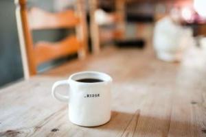 a full coffee mug with the word begin sits on a table