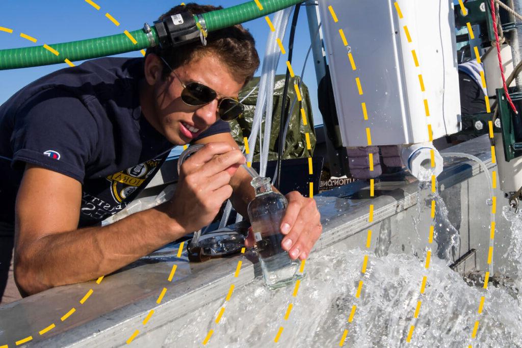 A researcher in the field filling a vial with water